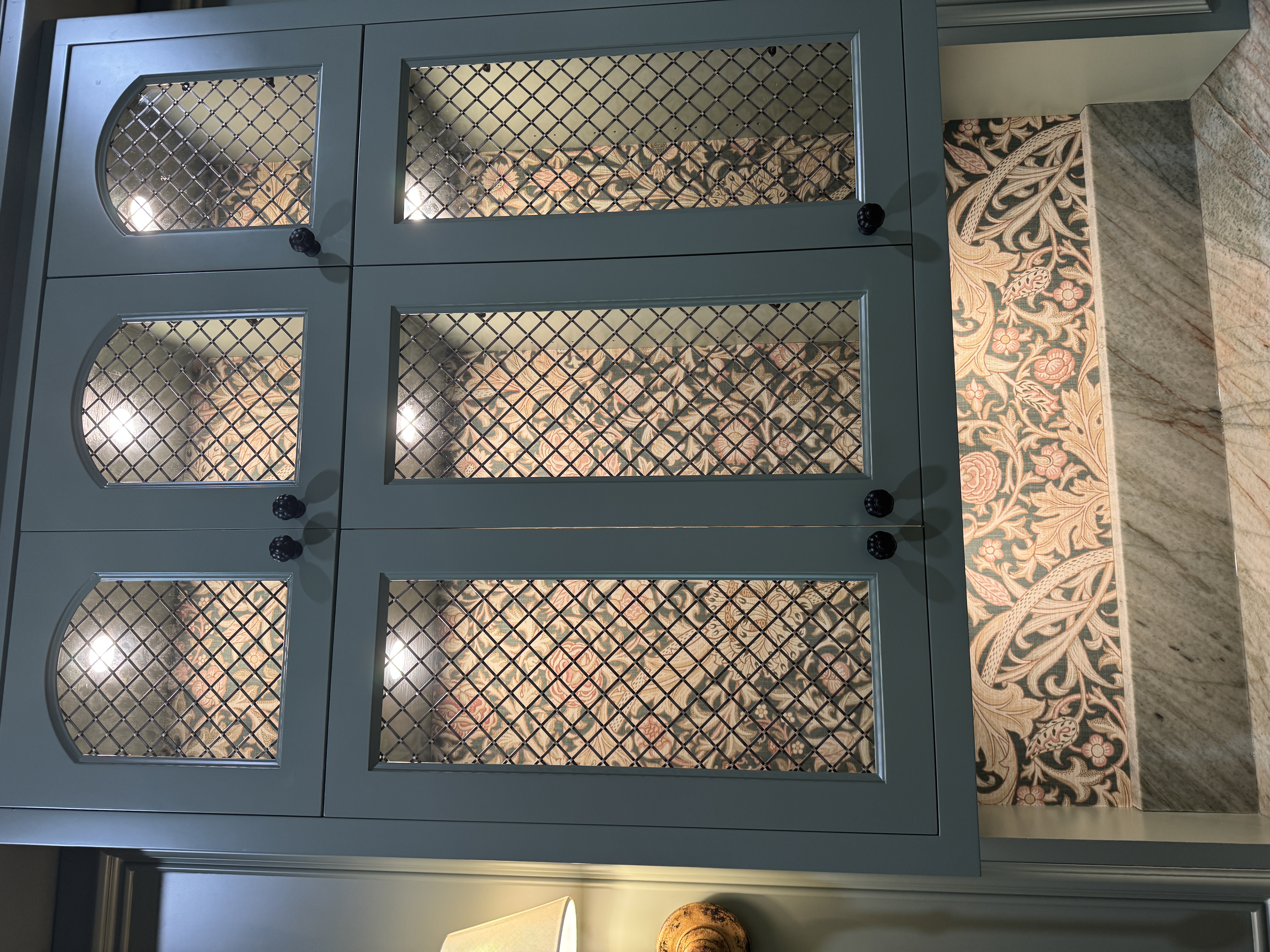 Patterned wallpaper installed behind blue glass-front display cabinets