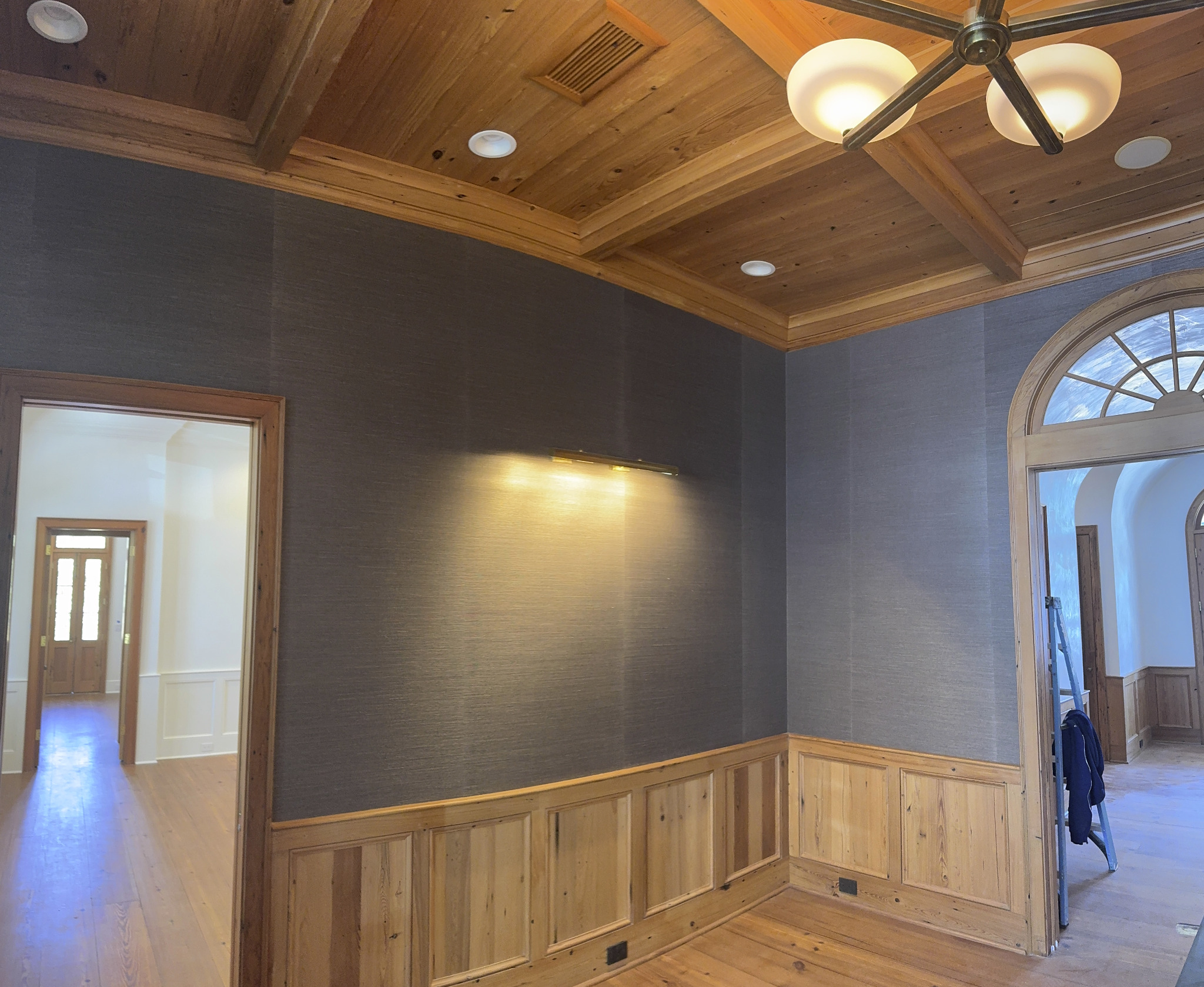 Textured dark grasscloth walls framed by natural wood paneling and ceiling beams