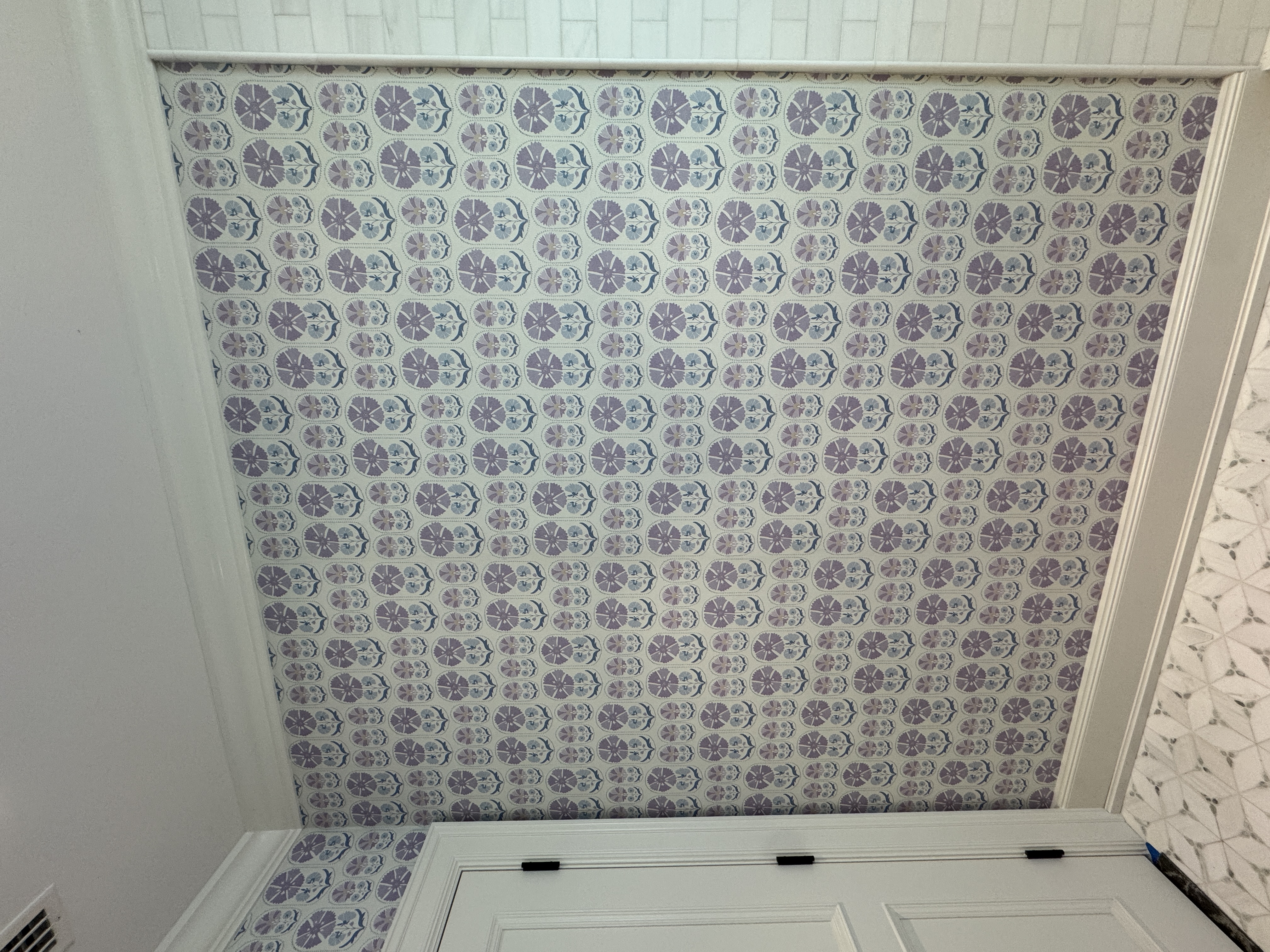 Blue and lavender repeating floral wallpaper aligned across an accent wall