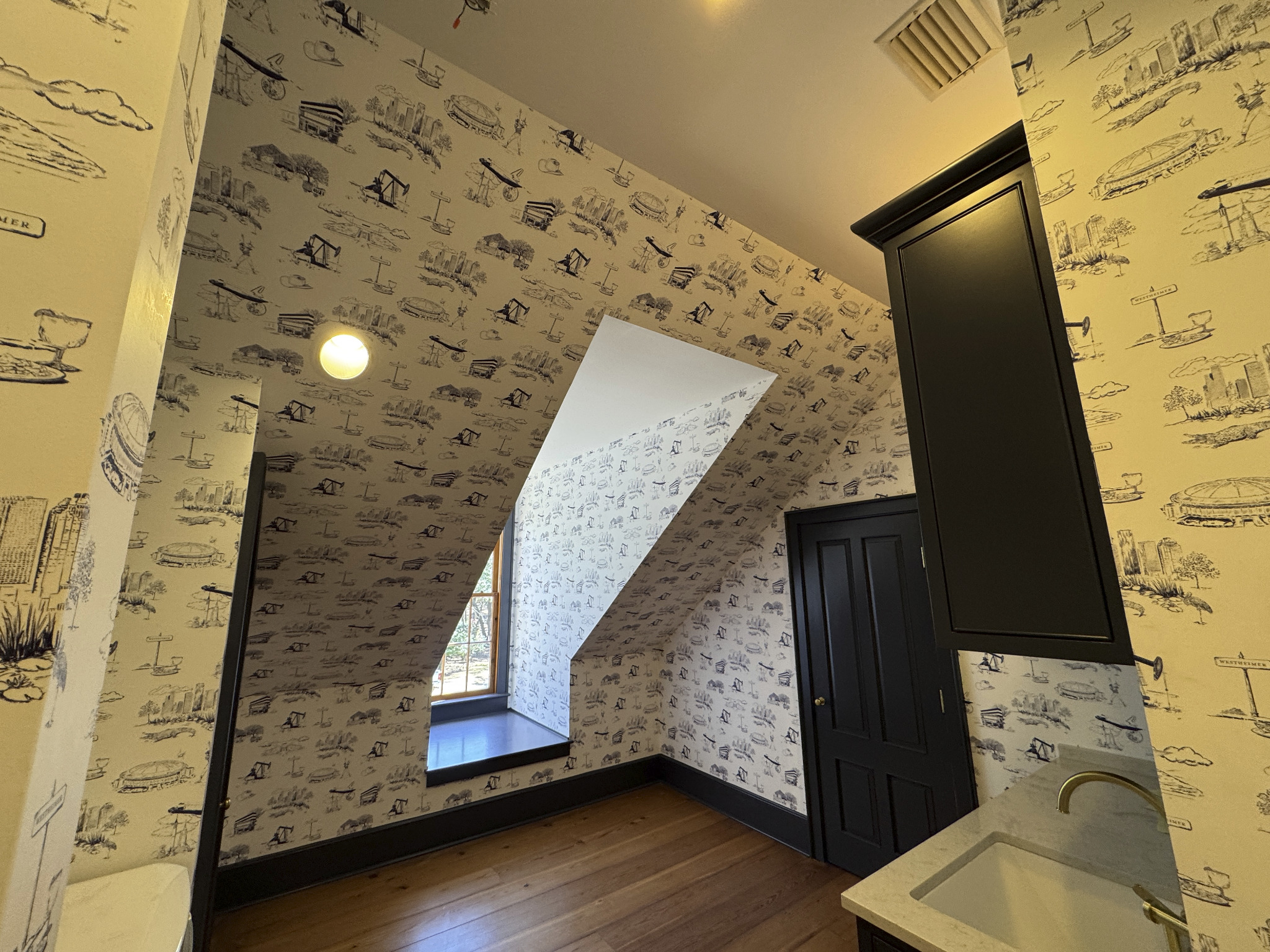 Illustrated wallpaper continues across walls and a sloped ceiling around a dormer window